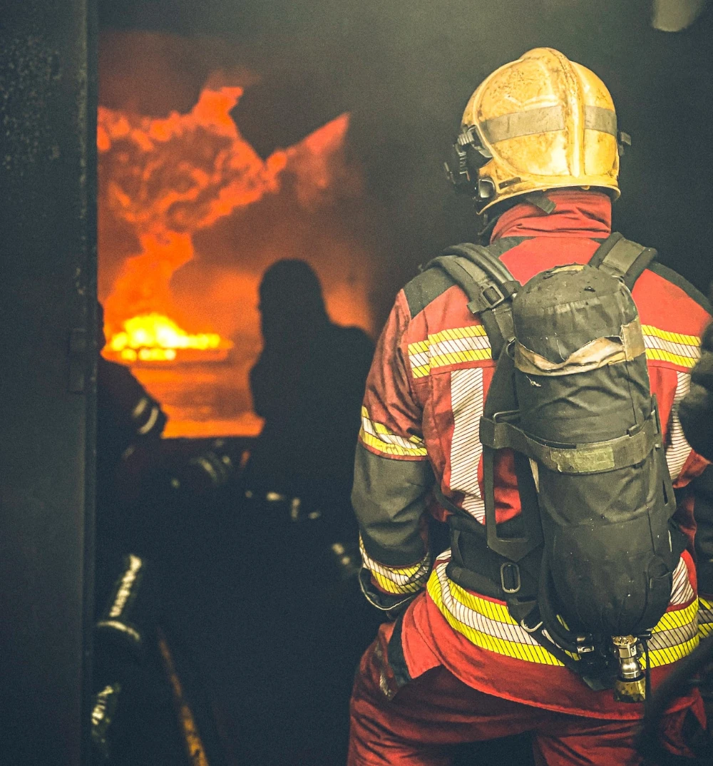 Feuerwehrmann steht am Türeingang und löscht ein Feuer im Haus